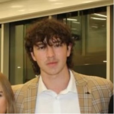 Portrait of Evan Poirier in a tan checked blazer.