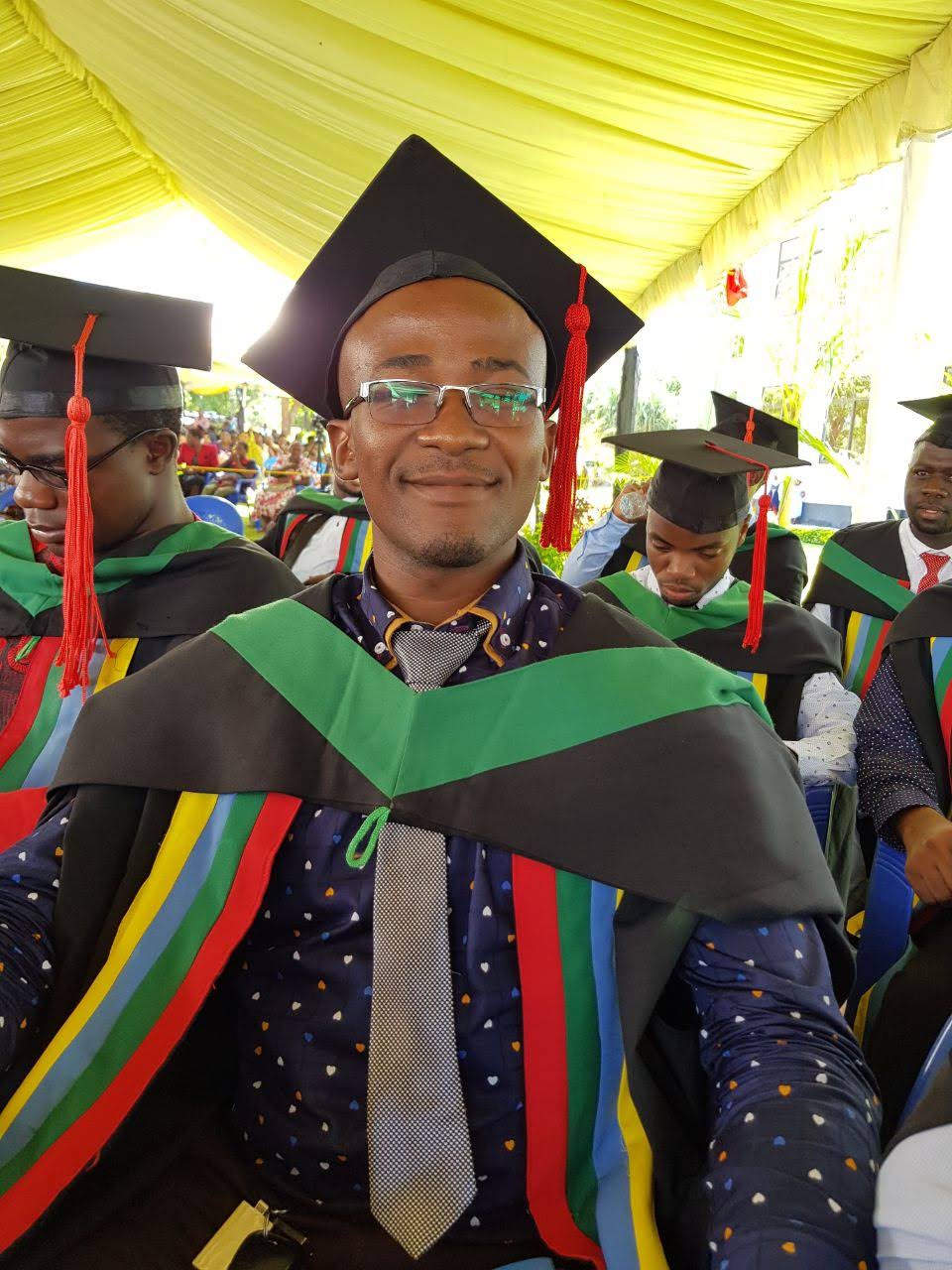 Davis Amani in academic regalia at graduation.