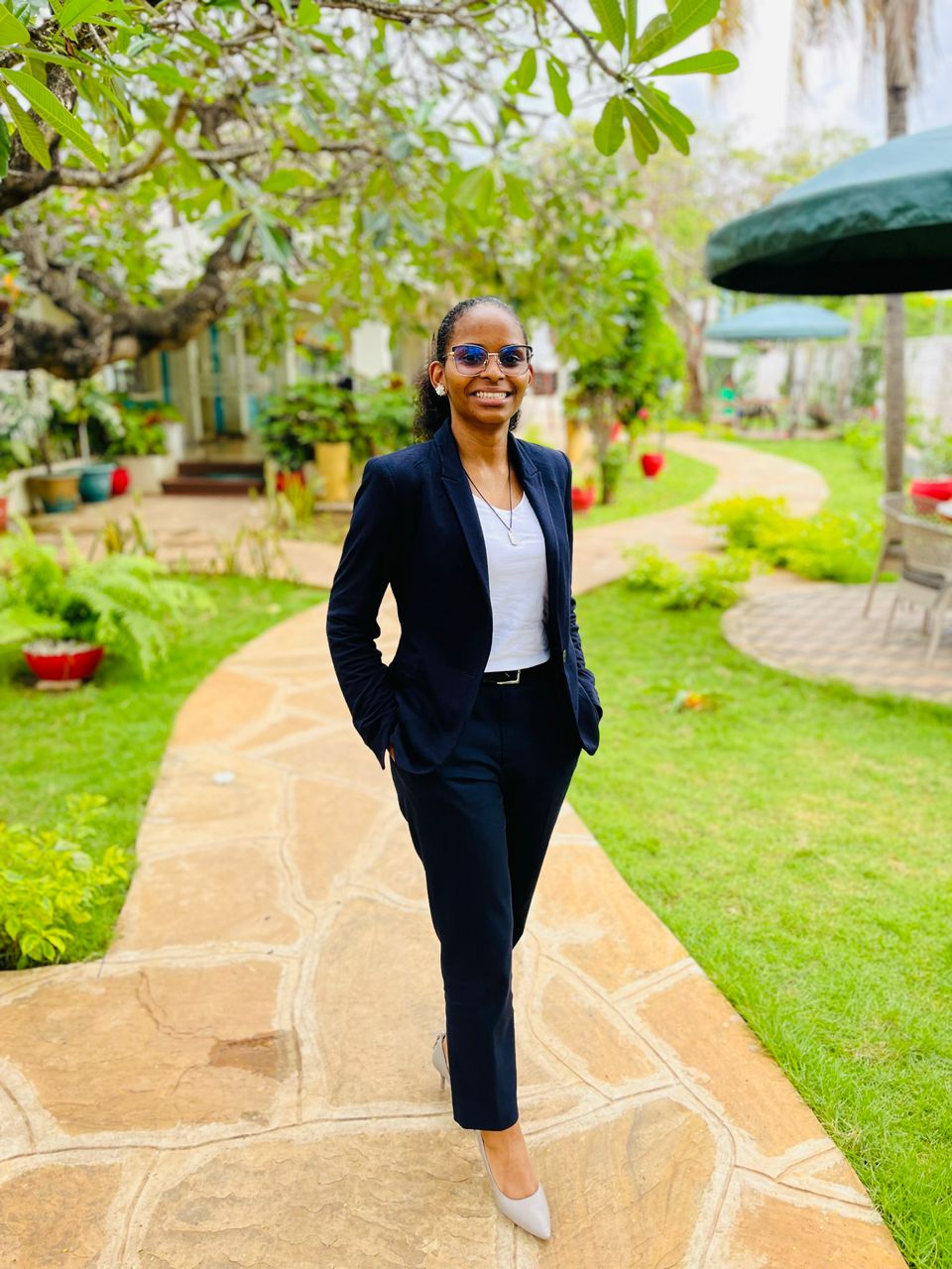 Full-body professional portrait of Jackline Ngowi in a navy suit.