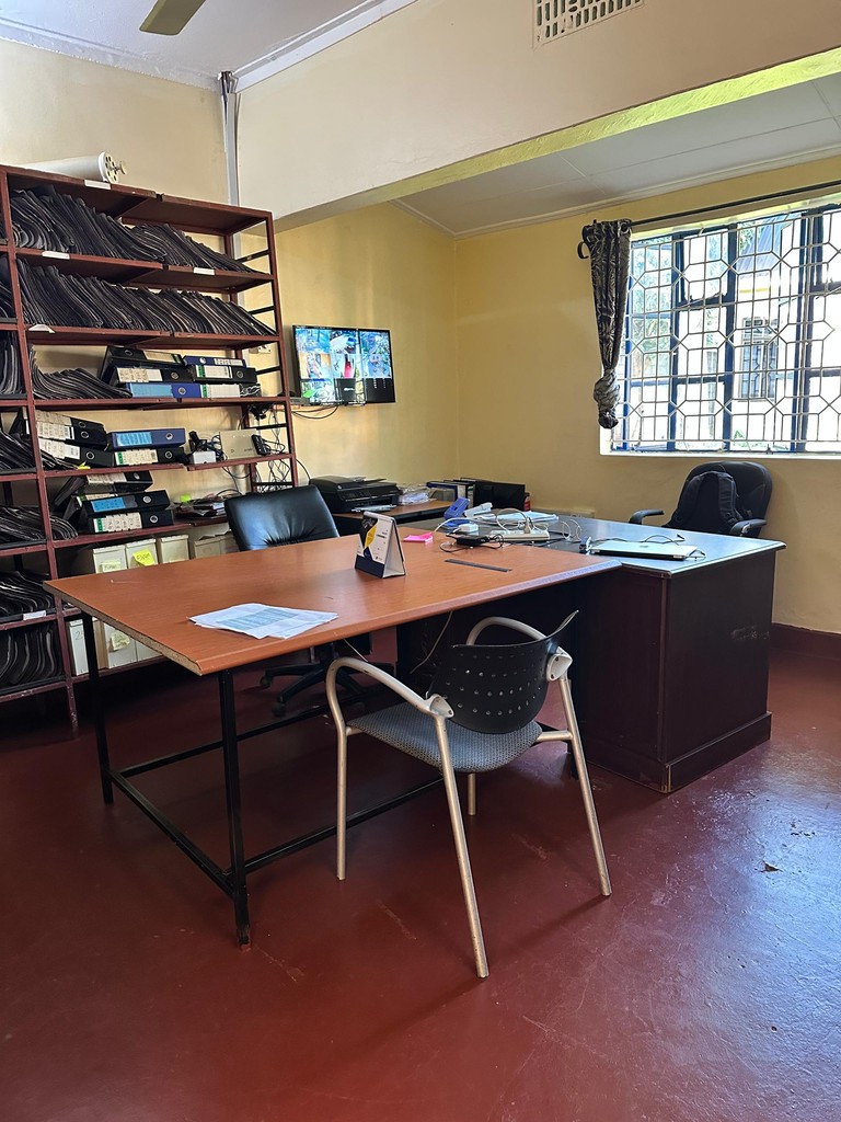 An office with a desk, chairs, bookshelves and a window.